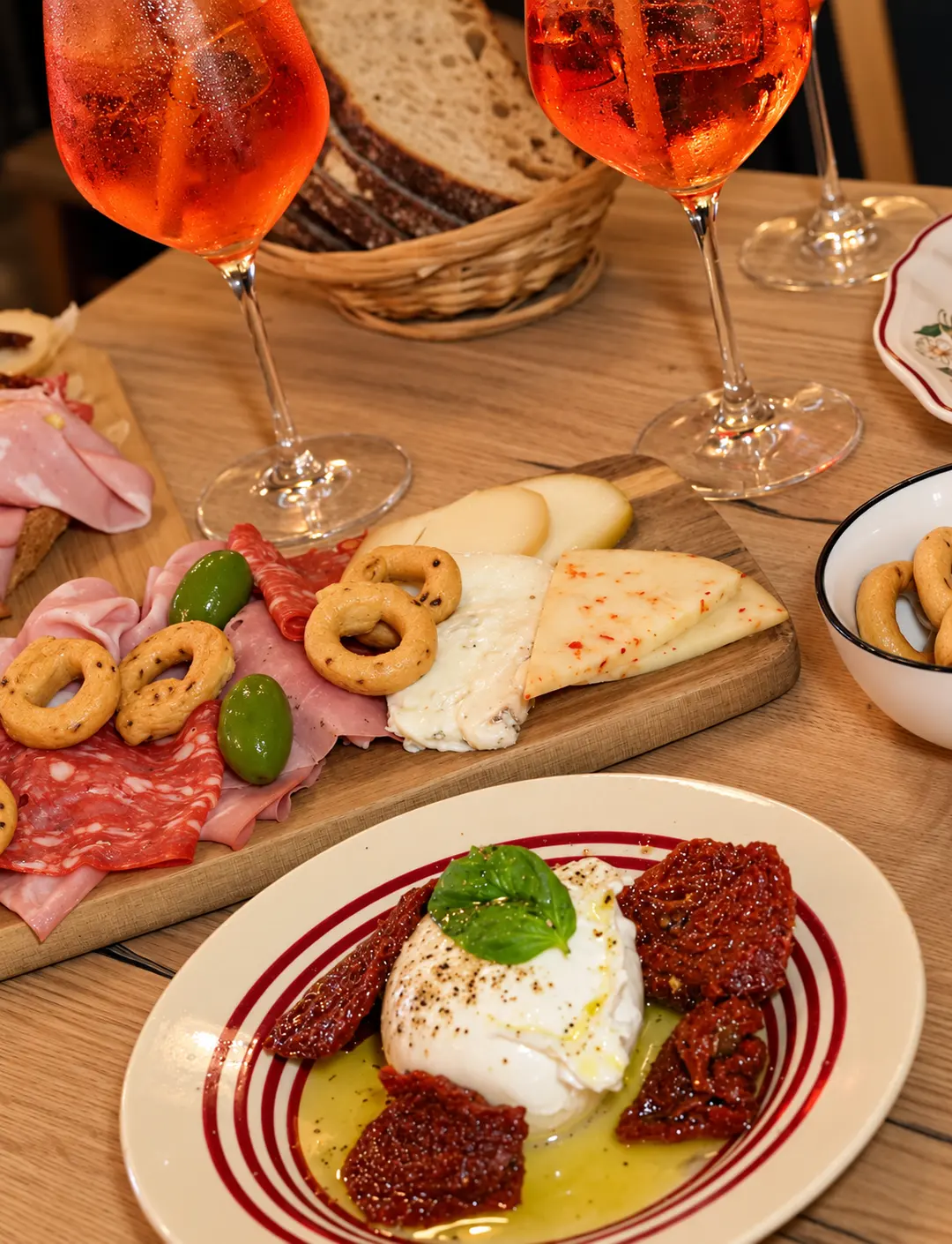 Une table d'aperitivo : spritz, burrata, charcuterie et fromages.