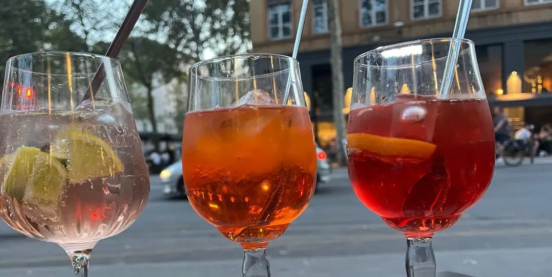 Trois verres d'aperitivo sur une table en terrasse, en fin de journée.