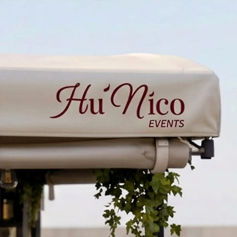 L'auvent du Piaggio, marqué du logo Hu'Nico Events, et ses feuillages.