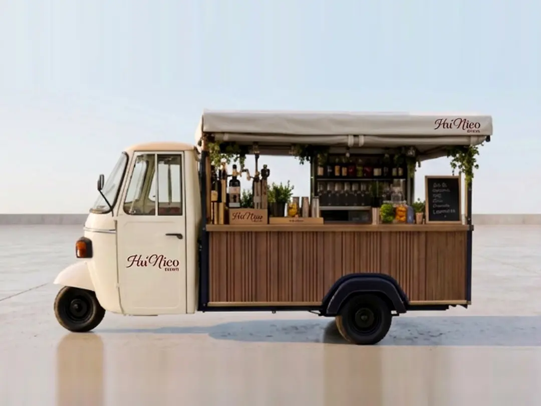 Le Piaggio Aperitivo de la Maison, vu de profil : bar en bois sous un auvent, bouteilles et plantes aromatiques.