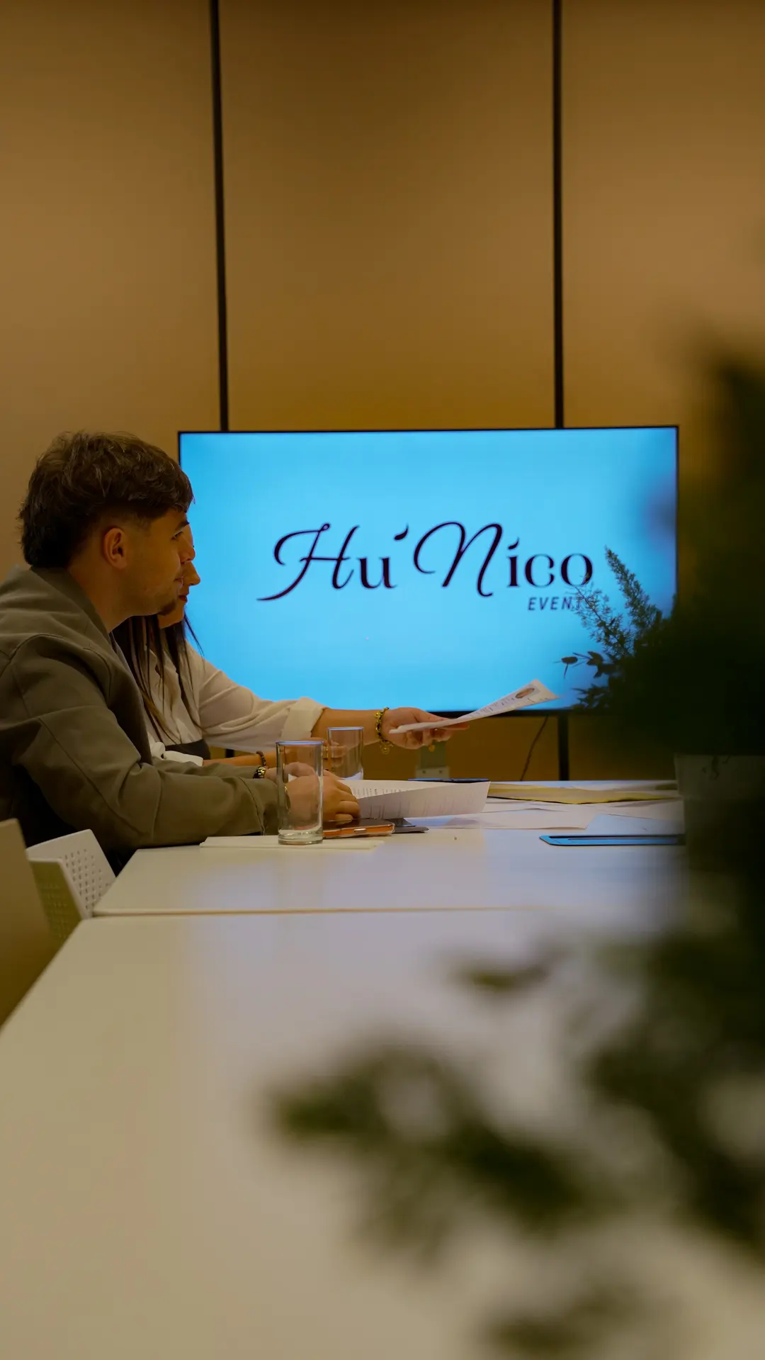 Une réunion autour d'une table, le logo Hu'Nico Events à l'écran.